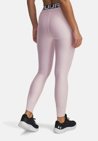 Leggings attivi rosa con una cintura alta nera, texture liscia, design aderente e cuciture a contrasto. Indossati con scarpe da ginnastica nere.