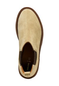 Zapato sin cierre de ante beige con suela de goma marrón. Paneles laterales elásticos, punta redondeada y un pequeño lazo en el talón para facilitar su colocación.