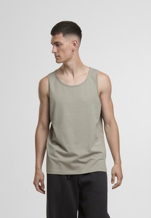 Helles khakifarbendes Tanktop mit Rundhalsausschnitt, ärmellosem Design und weichem Baumwollmaterial. Kombiniert mit dunklen, locker sitzenden Hosen.
