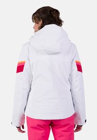 Witte waterdichte jas met capuchon, met kleurrijke gestreepte accenten in roze, oranje en rood op de mouwen. Soepele textuur.