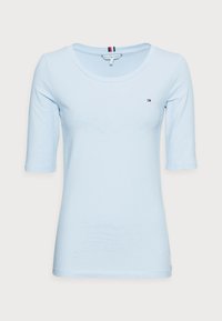 Světle modré tričko s dlouhým rukávem a kulatým výstřihem, vyrobené z bavlny, s malým logem na hrudi a přiléhavými rukávy.
