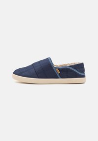 Navy quilted slip-on slippers with a soft inner lining, padded texture, and light beige rubber outsole; features a small logo on the side.