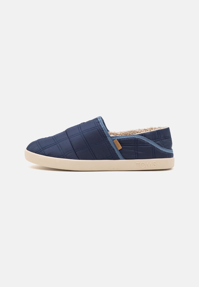 Navy quilted slip-on slippers with a soft inner lining, padded texture, and light beige rubber outsole; features a small logo on the side.