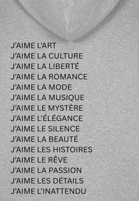 Hoodie gris avec une poche kangourou à l'avant, ornée de texte imprimé noir listant des phrases commençant par "J'aime" en français.