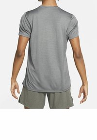 Grå kortärmad skjorta i andningsbart material, med rund halsringning och avslappnad passform. Bakifrån visas en jämn textur och flödande design.