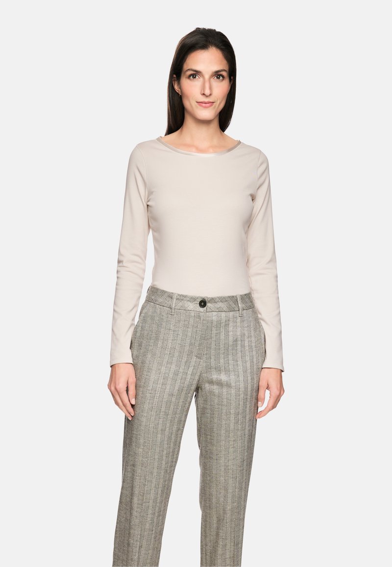 Beige Langarmoberteil aus glattem Stoff, kombiniert mit grauen, gestreiften Hosen mit Knopfverschluss und einer lässigen Passform.