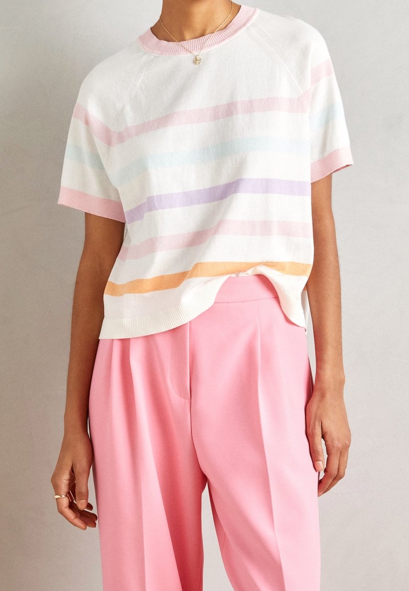 Suéter de manga corta en blanco con patrones de rayas en tonos pastel; presenta un escote redondo y dobladillo acanalado; combinado con pantalones de pierna ancha en rosa.