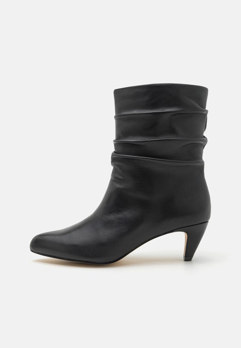 Botte en cuir noire mi-mollet avec tige souple et bout pointu, dotée d'un petit talon incliné.