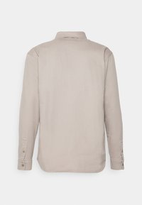 Ljusbeige långärmad skjorta med en slät yta, knappmanschetter och en klassisk krage. Har en rak fåll och design med ryggsöm.