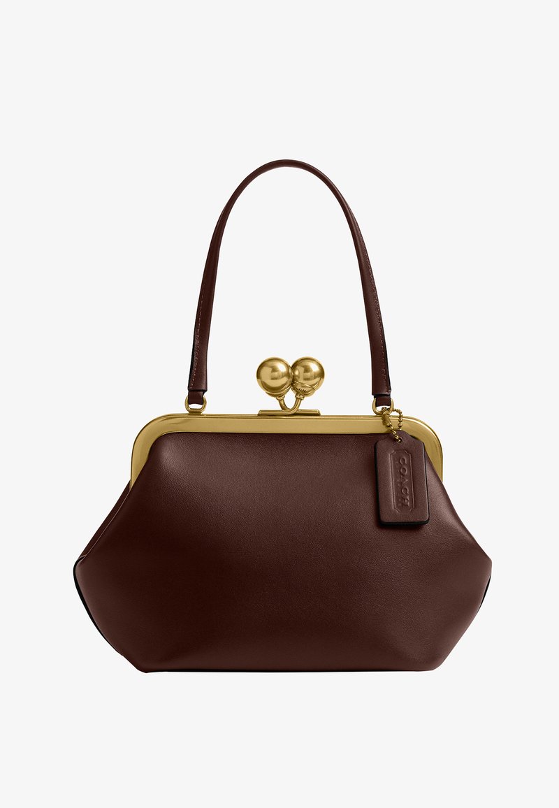 Sac à main en cuir marron foncé avec armature et fermoir en métal doré, bandoulière unique, et étiquette rectangulaire en cuir attachée.
