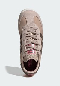 Bež tenisica sa gornjim dijelom od brušene kože i mrežastog materijala, s tamnosmeđim prugama, teksturiranim vrhom cipela i ružičastim logotipom na jeziku.