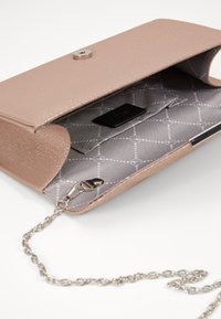 Light pink textured faux leather clutch with a silver snap closure and chain strap. Interior features a gray patterned lining and pocket.