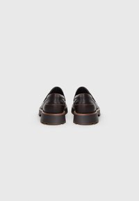 Chaussures en cuir marron à enfiler avec un profil bas, bout arrondi et semelle en caoutchouc contrastante. Coutures décoratives le long de la tige.