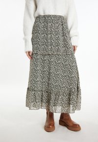 Maxi-jurk met bloemenpatroon in donkergroen met witte bloemen, gelaagd ontwerp, lichtgewicht stof, elastische tailleband, gecombineerd met bruine enkellaarsjes.