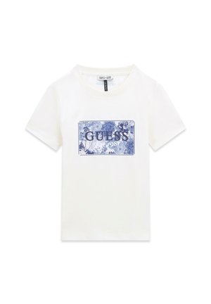 T-shirt blanc à manches courtes avec un imprimé rectangulaire fleuri bleu et le texte "GUESS 1981" sur la poitrine.