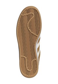 Sula av sko med ett vågigt, strukturerat mönster i brunt gummi. Innehåller vita ränder på sidorna och en överlag neutral färgskala.
