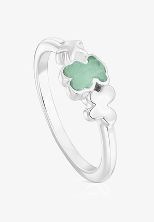 Srebrny pierścień z dwoma motylkami, z których jeden jest wypełniony jasnym zielonym kamieniem, na białym tle.