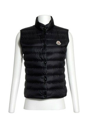 Veste matelassée noire sans manches avec col montant et fermeture à boutons sur un torse de mannequin blanc.