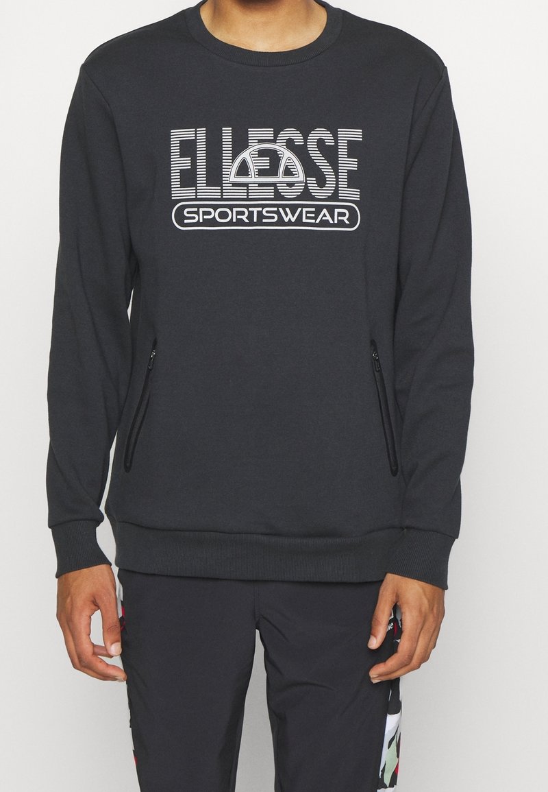 Sweat-shirt gris foncé à encolure ronde, avec un logo blanc "ELLESSE SPORTSWEAR" et des poches latérales zippées. Tissu doux, poignets côtelés.