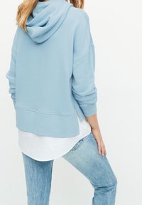 Felpa blu chiaro realizzata in un tessuto morbido, con un taglio rilassato, polsini a coste e un design comodo e leggermente cropped.