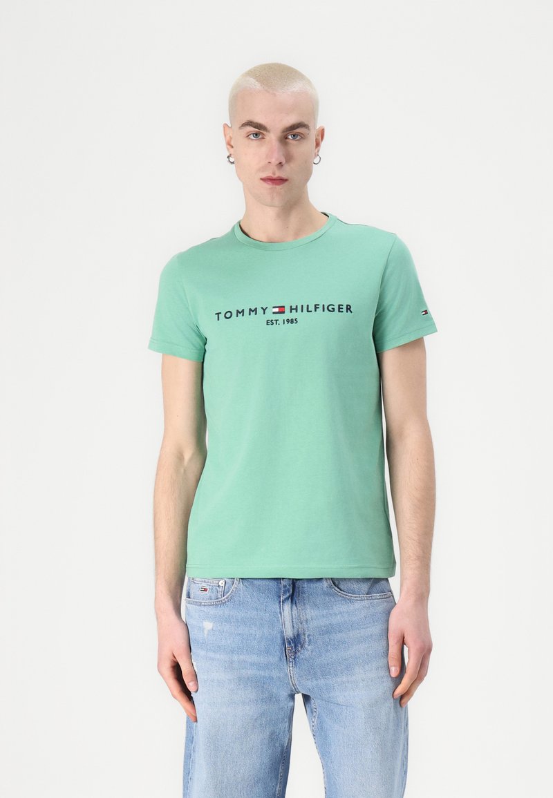 Green cotton t-shirt featuring a crew neck, short sleeves, and black "TOMMY HILFIGER EST. 1985" logo across the chest.