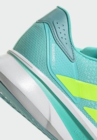 Turquoise athletic shoe with mesh upper, yellow accents, textured finish, and a cushioned white sole. "Duramo SL2" label visible.