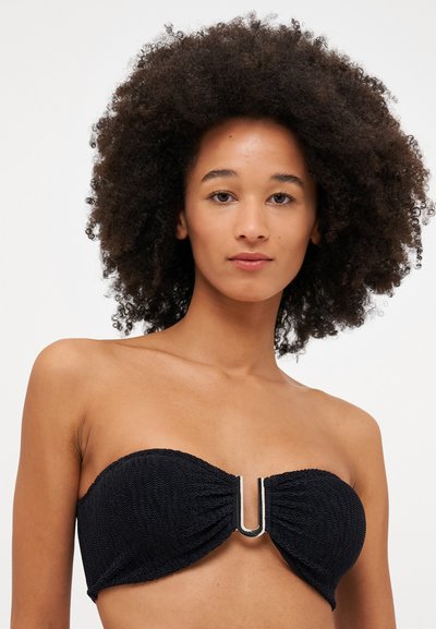 Svart, strapless bikinioverdel med teksturert stoff, som har en rynket design og en sølvfarget U-formet aksent i midten.