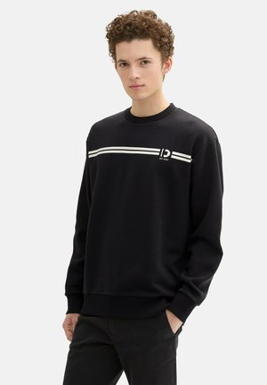 Sudadera negra de manga larga, cuello redondo, con franjas horizontales blancas en el pecho, puños acanalados y bajo acanalado.