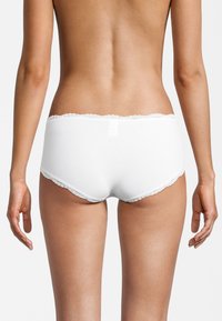 Weiße Baumwoll-Boyshorts mit strukturiertem Ribbenmuster und einer zarten Spitzenkante am Bund, die sich von glatter Haut abheben.