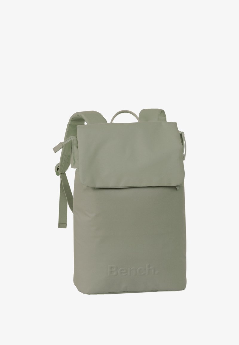 Light green fabric backpack with a fold-over flap, adjustable straps, top handle, and embossed brand logo on the front panel.