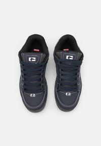 Navy blue sneakers with a textured fabric upper, padded collar, and contrasting white stitching. Features round laces and logo accents.