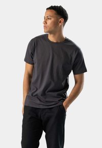 Grå bomuld t-shirt med korte ærmer, rund hals og en afslappet pasform. Båret med sorte bukser. Ingen mønstre eller yderligere detaljer synlige.