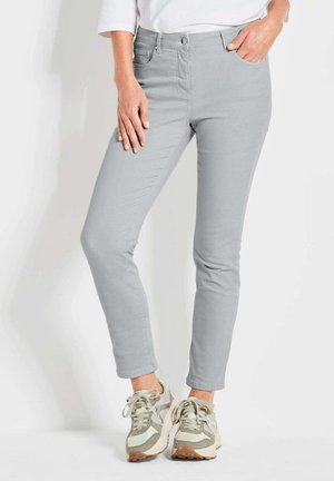 Lichtgrijze skinny jeans met een naadloos ontwerp, voorzakken en een middelhoge taille, gecombineerd met beige en grijze sneakers.