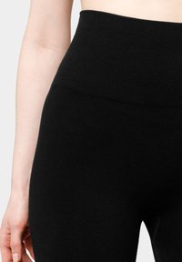 Zwarte geribde leggings met een hoge tailleband, gemaakt van een zachte, rekbare stof; heeft een gladde textuur en een lichaamsomsluitende pasvorm.