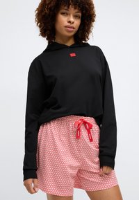 Zwarte hoodie met lange mouwen en een rood logo. Rood- en witte gemêleerde shorts met een koord. Zachte stof, comfortabele pasvorm, casual ontwerp.