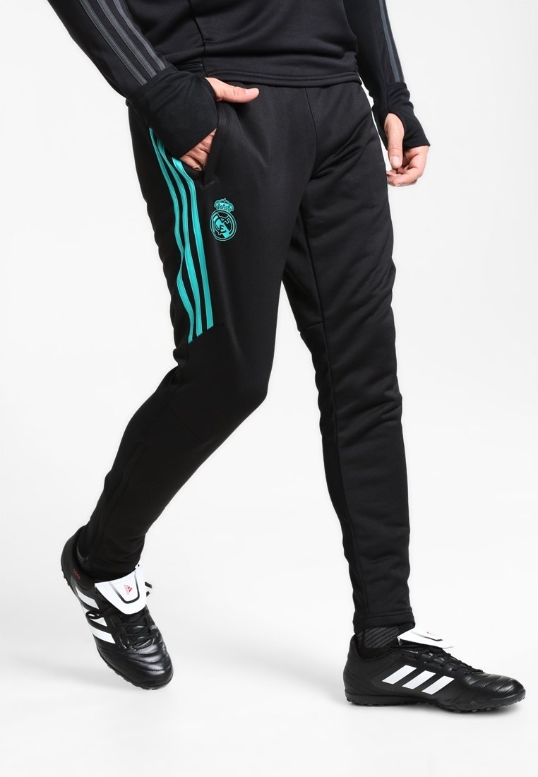Schwarze Sporthose mit türkisfarbenen Seitstreifen, ausgestattet mit dem Real Madrid-Logo. Hergestellt aus weichem Stoff, im tapered Fit mit Taschen.