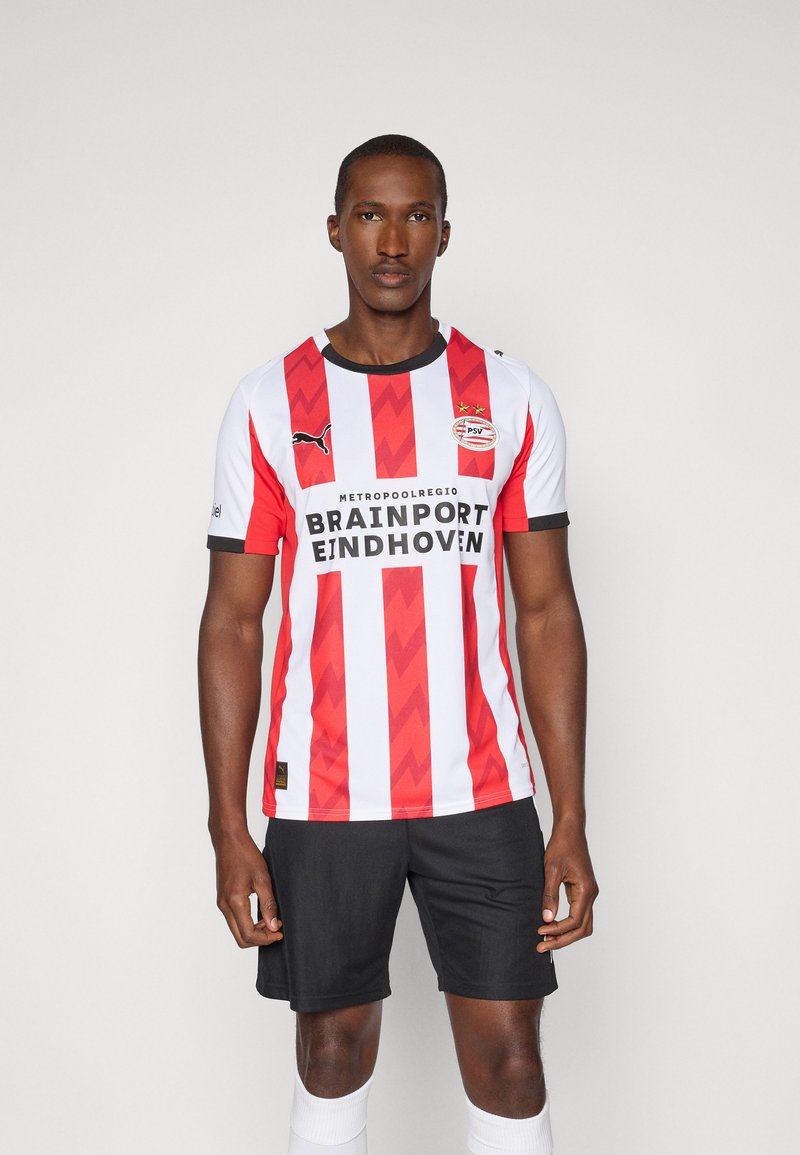Rød- og hvidstribet fodboldtrøje med et chevronmønster, sorte detaljer og sponsorlogo; parret med sorte shorts og hvide sokker.