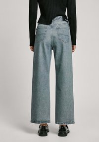 Ljusblå vida jeans med hög midja, tillverkade av denim; har två bakfickor och når till mitten av vristerna.