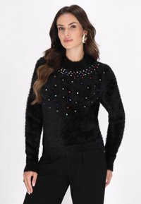 Sort fluffy sweater med juveltonede udsmykninger ved halsen og spredt over fronten. Lange ærmer og en tætsiddende design.