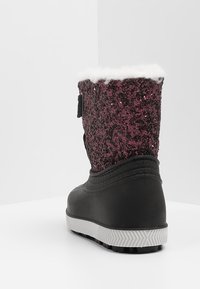 Black winter boot with white sole, maroon sequin upper, and white fuzzy lining shown from the back on a white surface.
