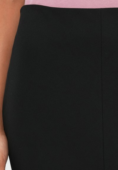 Jupe en tissu noir avec une texture lisse, présentant une coupe structurée et une taille rose en haut. Détail de couture visible au centre.