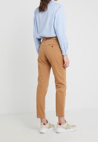 Chinos i beige med slim fit och bakfickor, kombinerat med en ljusblå skjorta och flerfärgade sneakers.