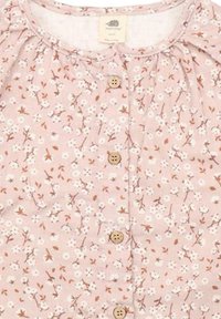 Rotes Blumenmuster Kleid mit kleinen weißen Blumen und braunen Akzenten, mit einem runden Ausschnitt, gerüschten Schultern und Holzknöpfen vorne.