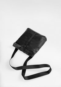 Borsa a tracolla nera realizzata in materiale liscio e resistente; presenta una tracolla regolabile, una chiusura a fibbia e il logo del marchio impresso sul davanti.