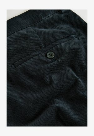 Melnas korduroja audumam ar rievotu tekstūru, ar vienu aizmugures kabatu un apaļu tumšu pogu aizdarē.