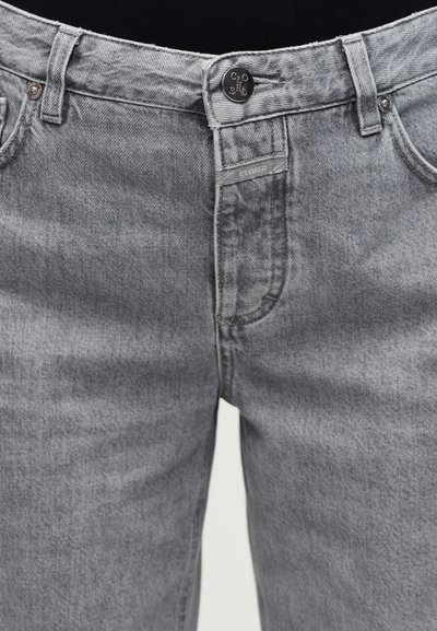 Jean en denim gris avec fermeture à boutons et fermeture éclair, poches avant, passants pour ceinture, et détails de texture délavée.