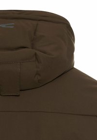 Brun polstret jakke med høj krave, med en quilted hardwaredetalje og en glat, mat tekstur. Logoet er synligt på kraven.