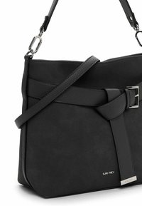 Bolso de cuero negro para llevar al hombro con correa ajustable, detalle de hebilla en el frente y pequeño logotipo metálico de la marca "SURI FREY" cerca de la parte inferior derecha.