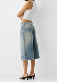 Ljusblå denimculotter med lös passform, rå kant och fram- och bakfickor. Matchas med en figurnära vit linne.