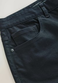 Donkerdenim broek met een standaard taille, voorzak, metalen knoopdetail en subtiele textuur. Gestikte naden en nette randen.